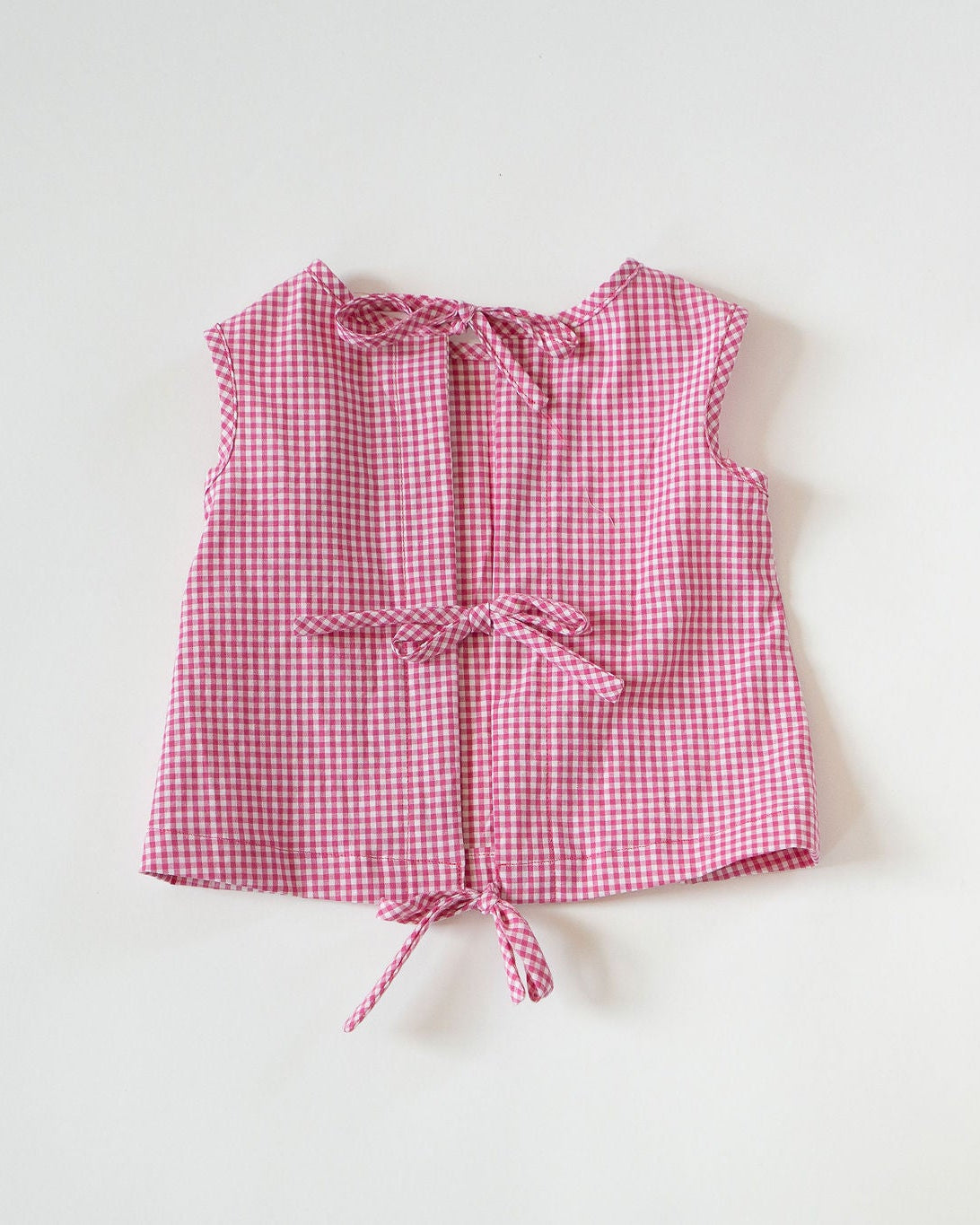 Pink checkered sleeveless top on a white background