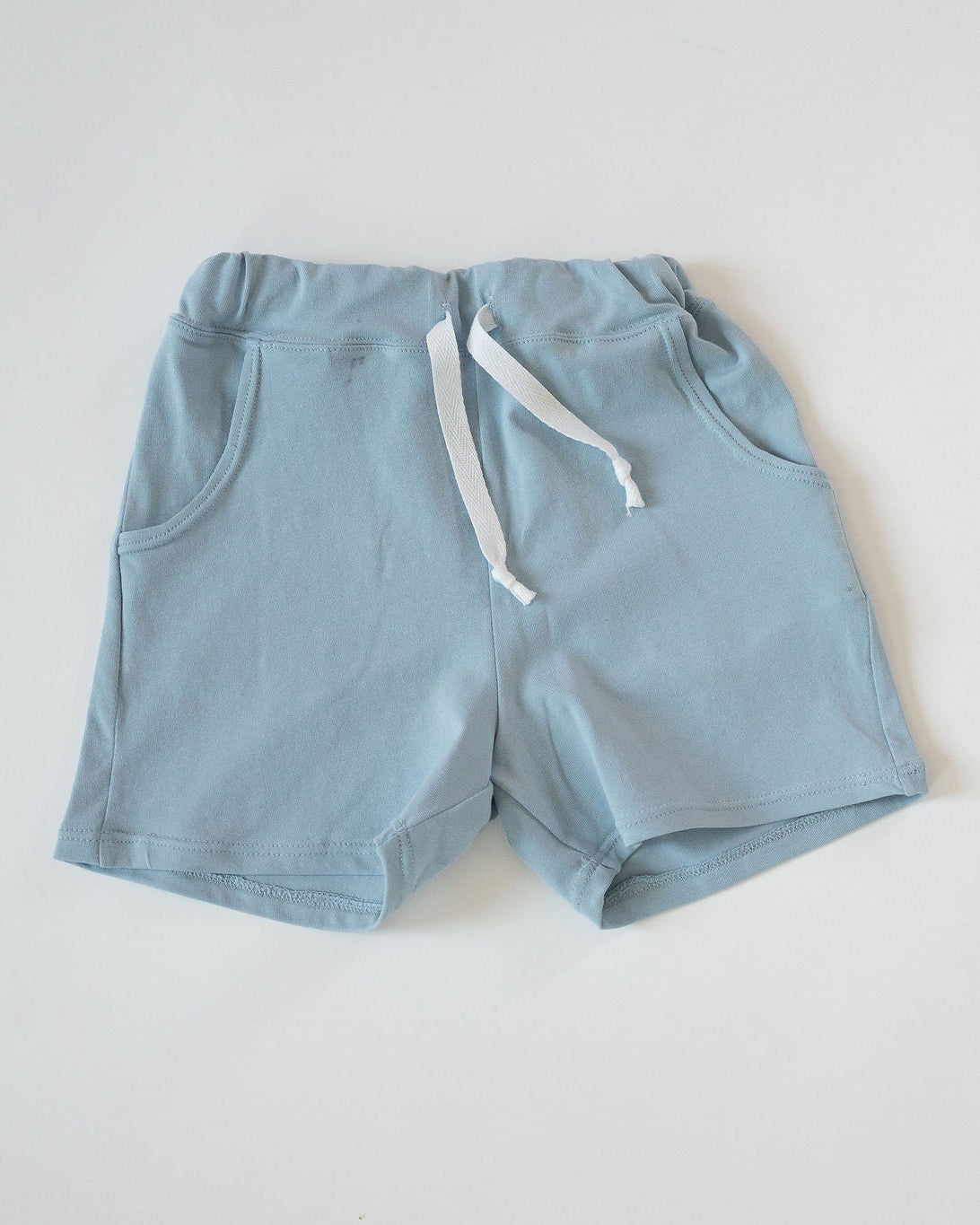 Light blue shorts with a white drawstring on a light gray background