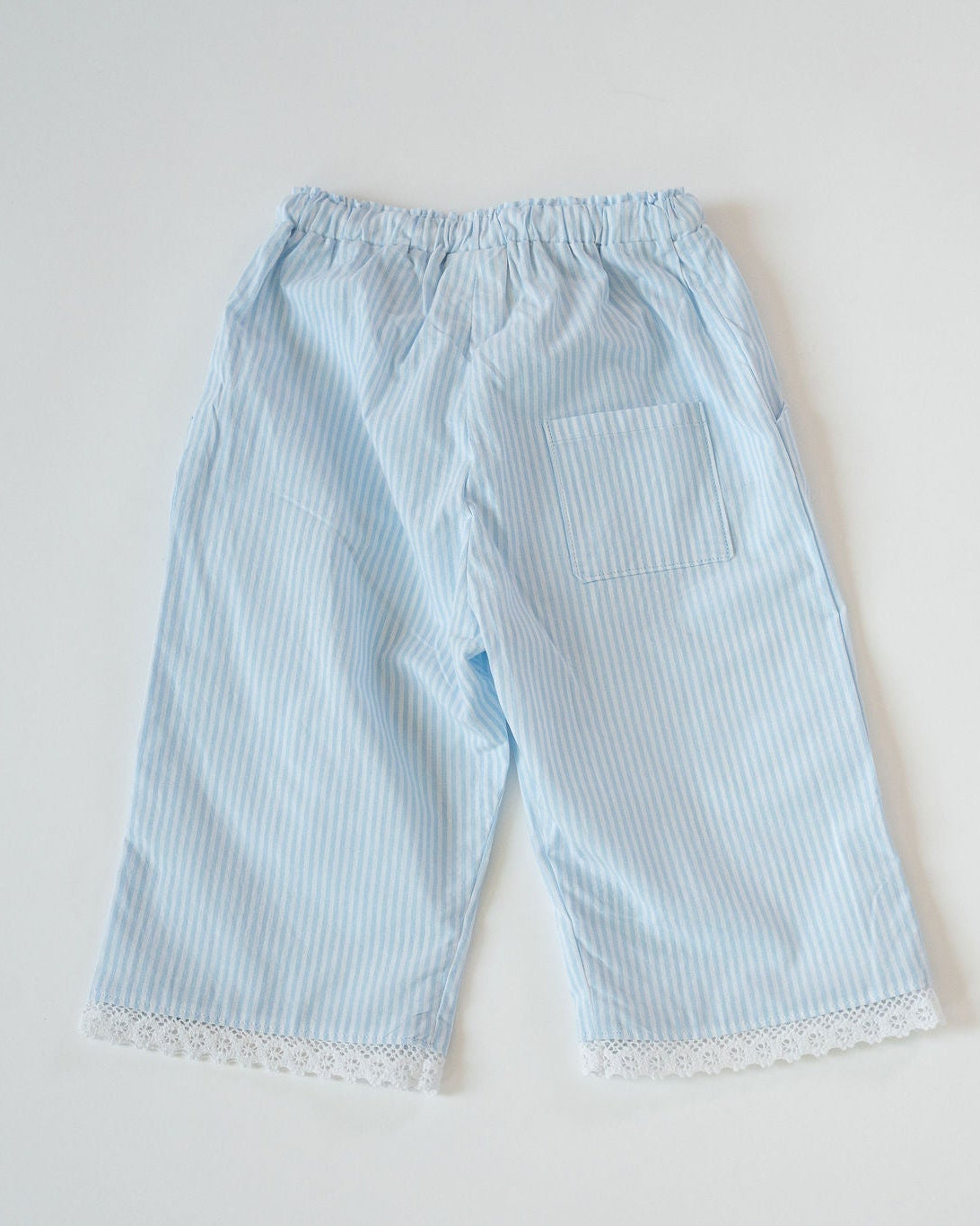 Light blue striped pants with lace trim on a white background