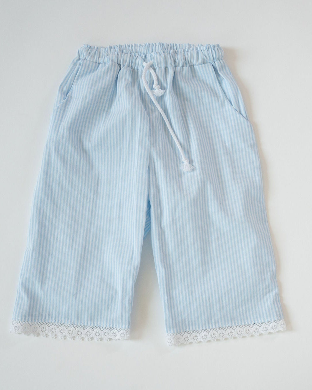 Light blue striped pants with lace trim on a white background
