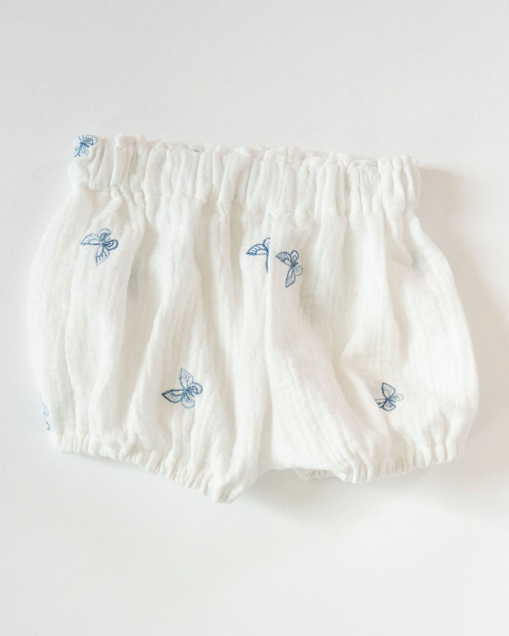 White baby bloomers with blue butterfly patterns on a white background