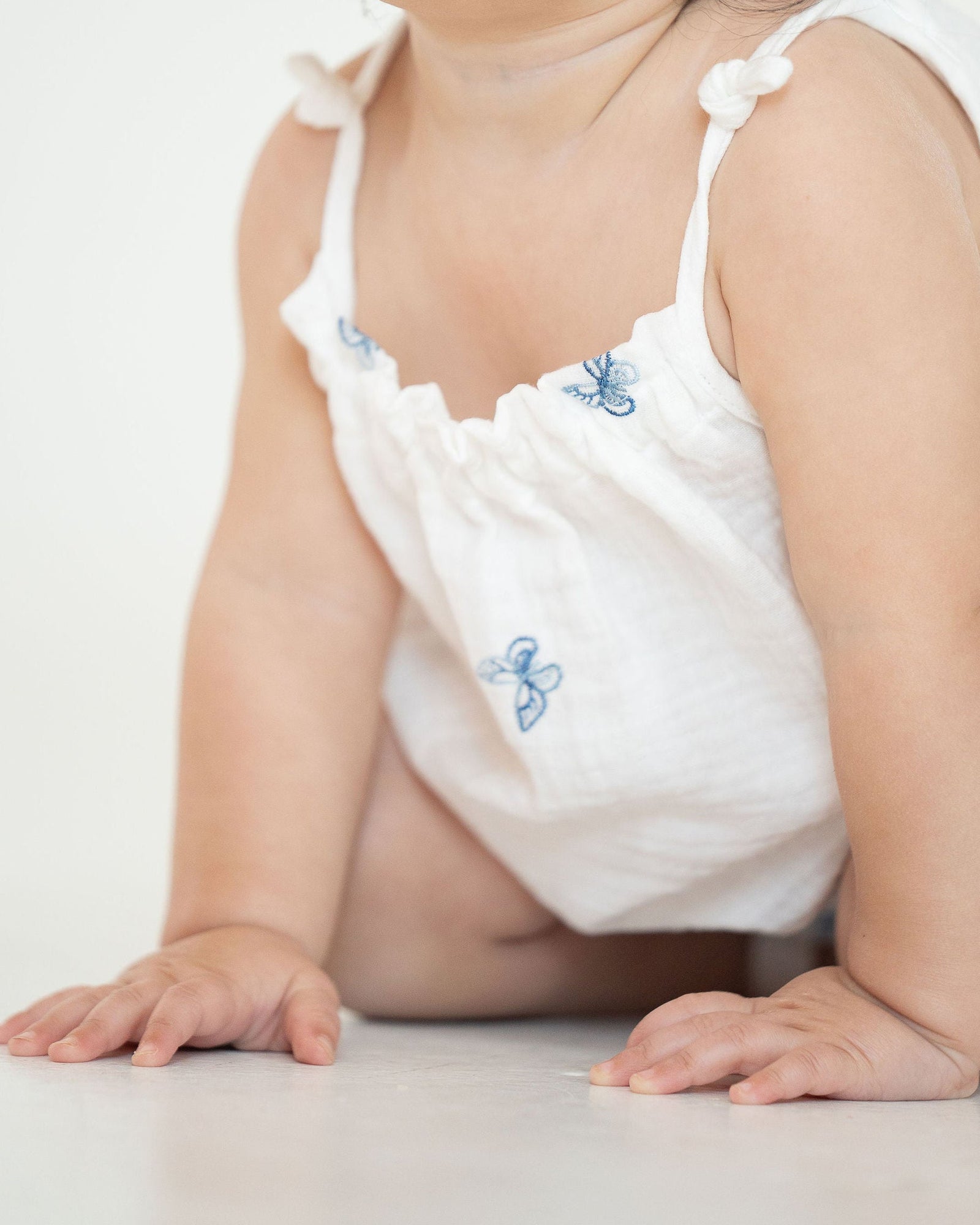 White baby tank with blue floral patterns on a white background