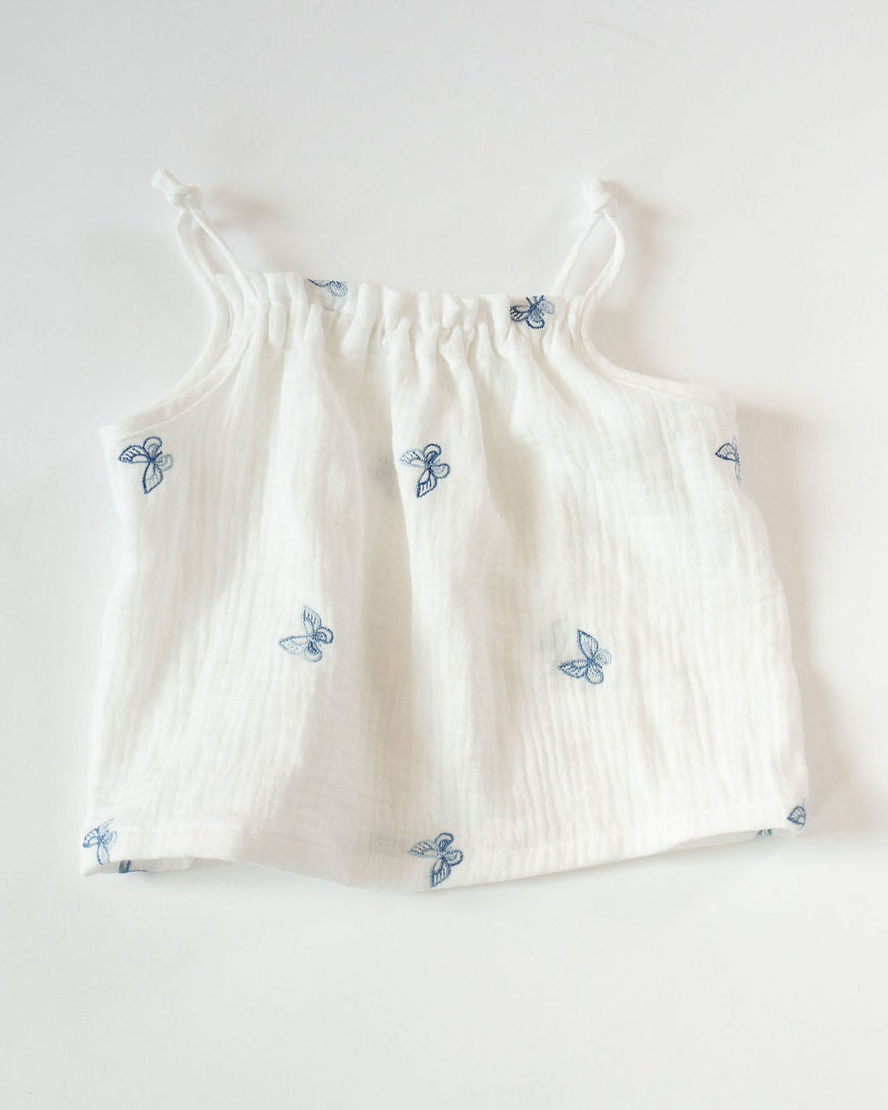 White baby tank with blue floral patterns on a white background