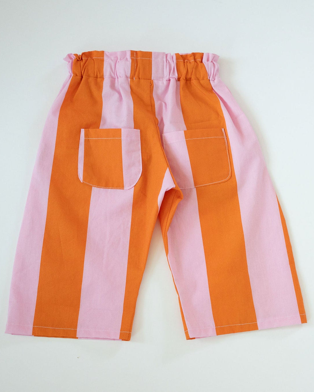 Striped pants with orange and pink vertical stripes on a white background
