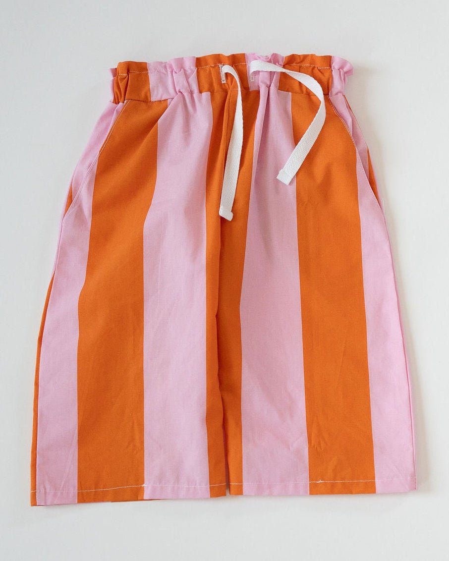 Pink and orange striped shorts with a drawstring on a light gray background