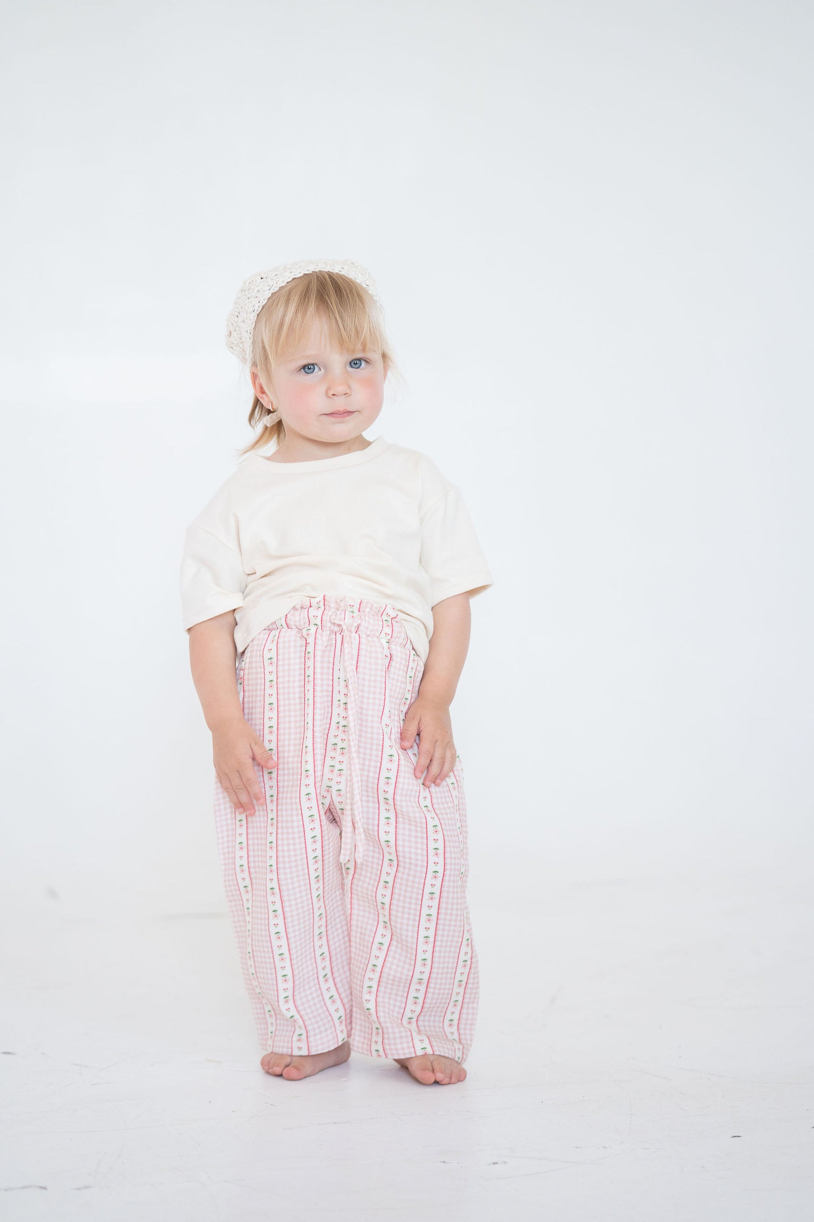 Child wearing a white shirt and pink striped pants on a white background