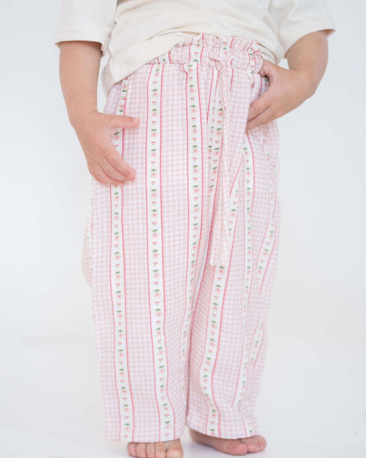 child wearing pink checkered pants on a white background