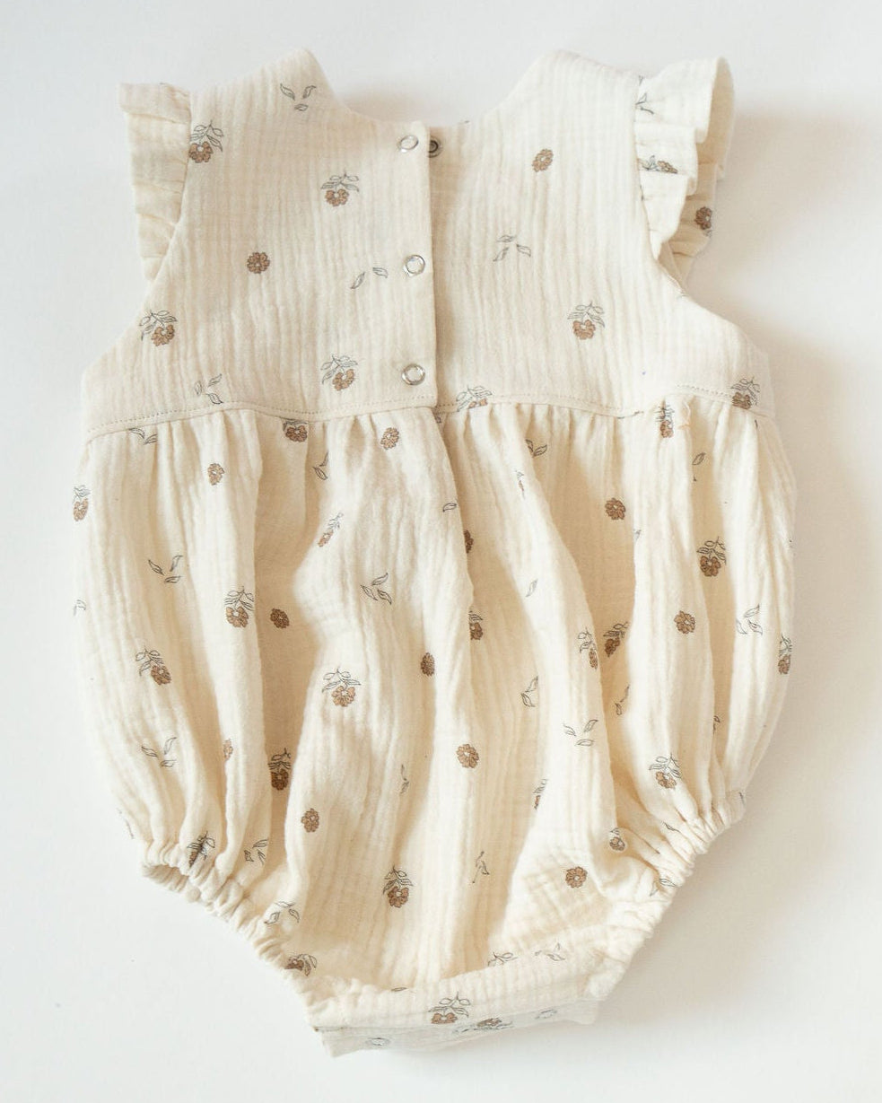 Beige baby romper with small patterns on a white background