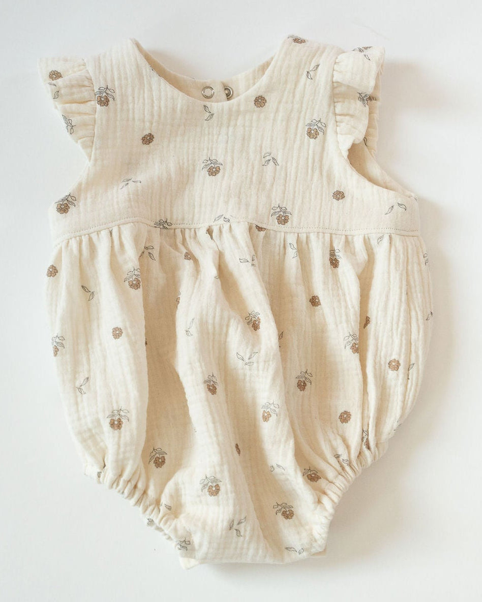 Beige baby romper with small patterns on a white background