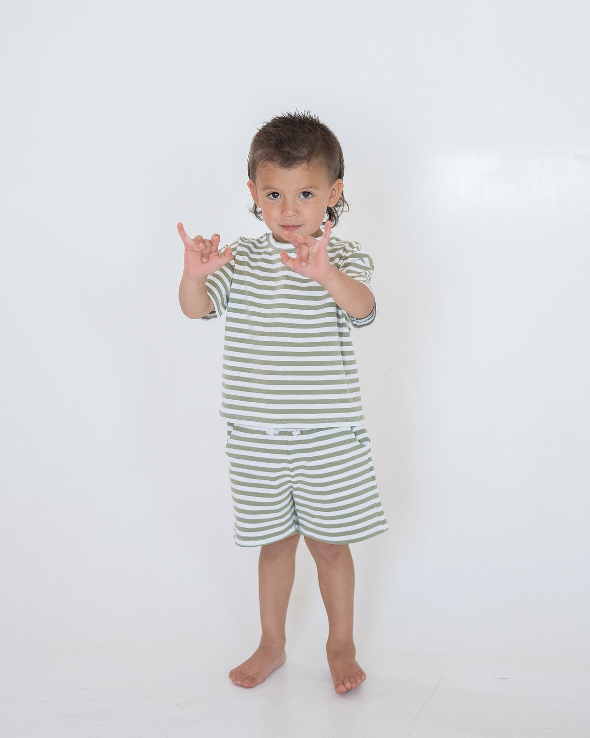 Child wearing a green and white striped outfit on a white background