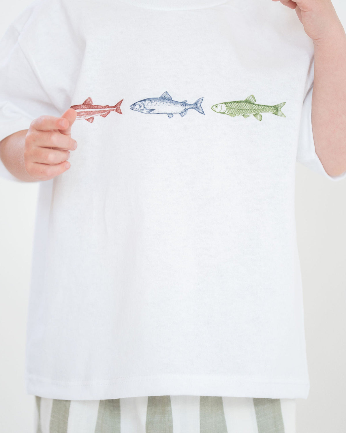 Person wearing a white shirt with printed fish designs on a plain background