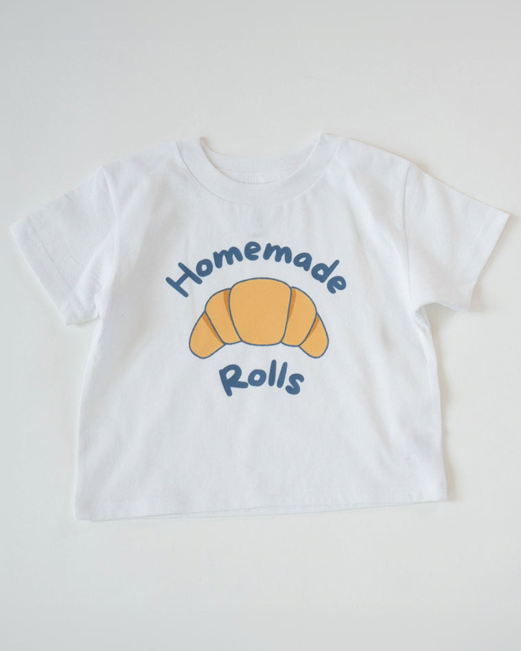 White t-shirt with a croissant graphic and 'Homemade Rolls' text on a white background