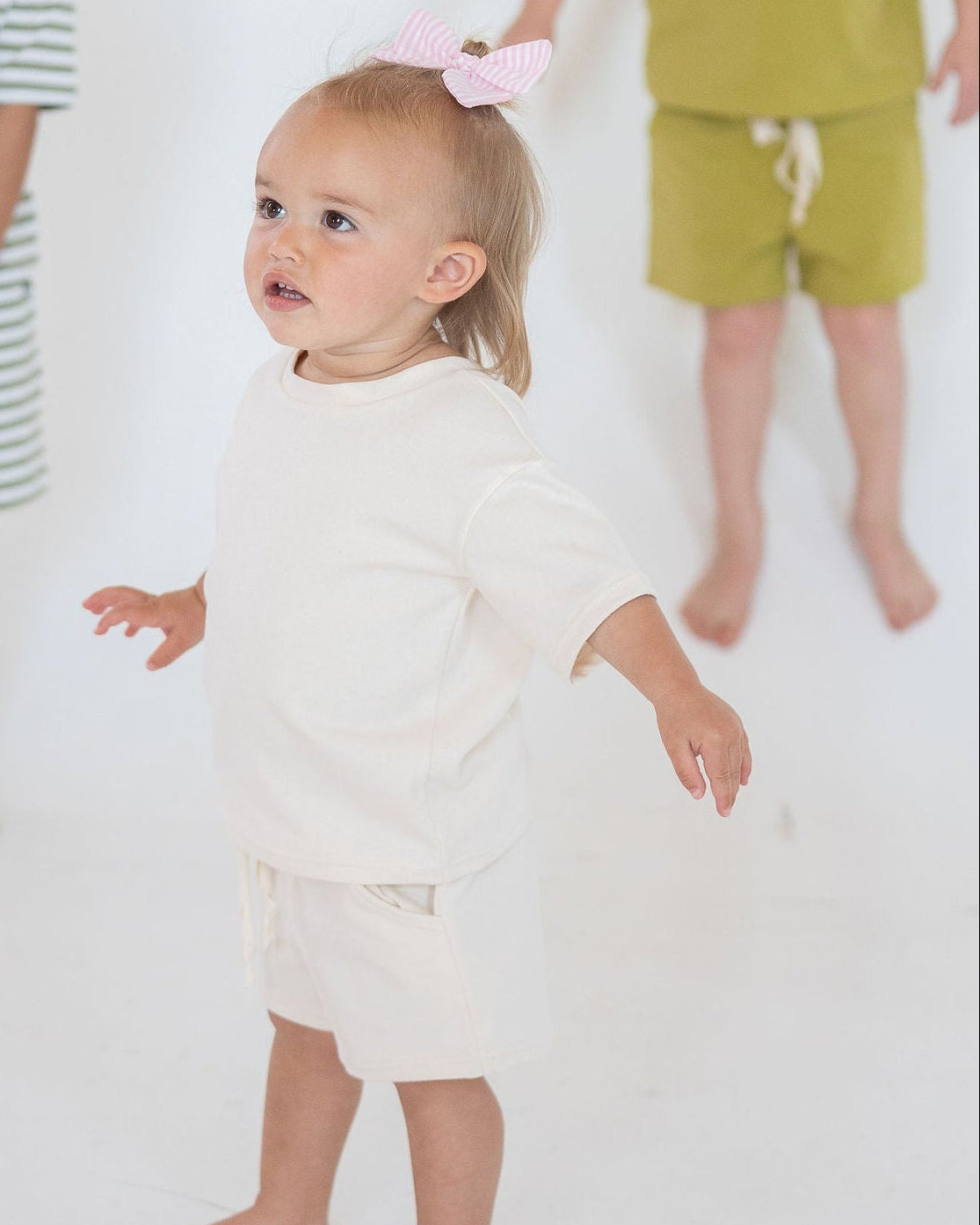 Three children in colorful outfits standing on a white background