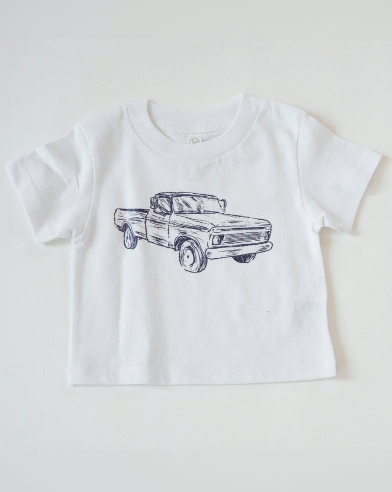 White t-shirt with a blue truck graphic on a white background