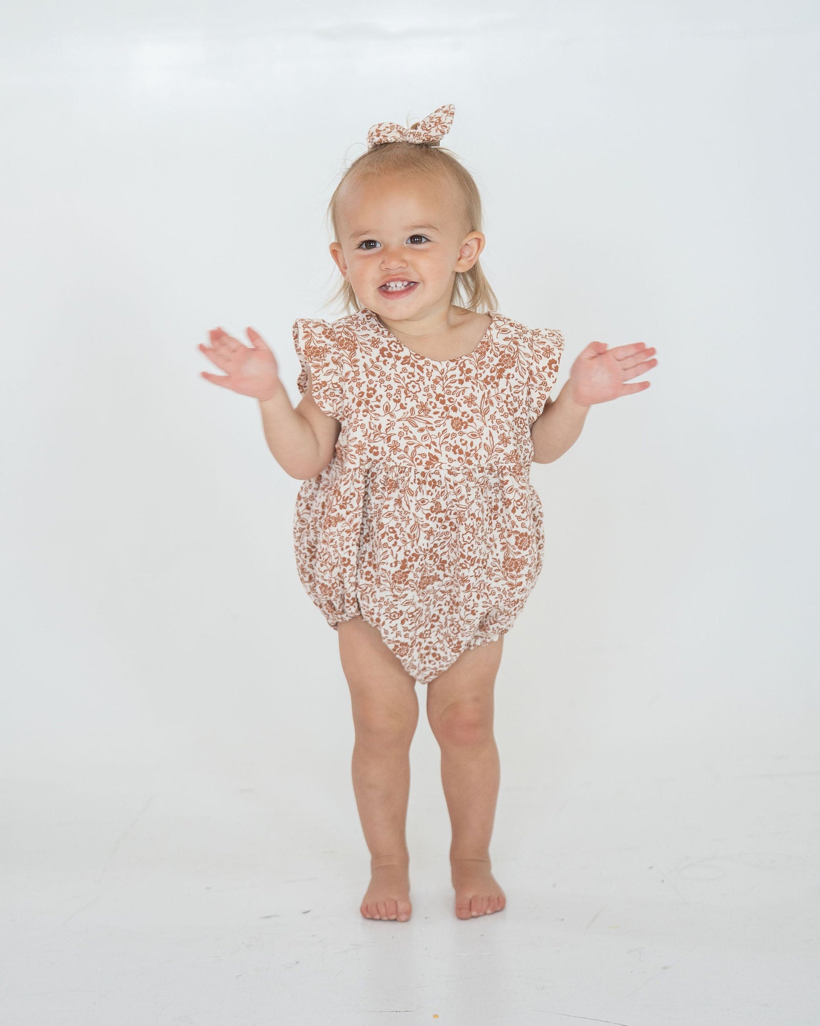 Brown floral-patterned baby romper on a white background