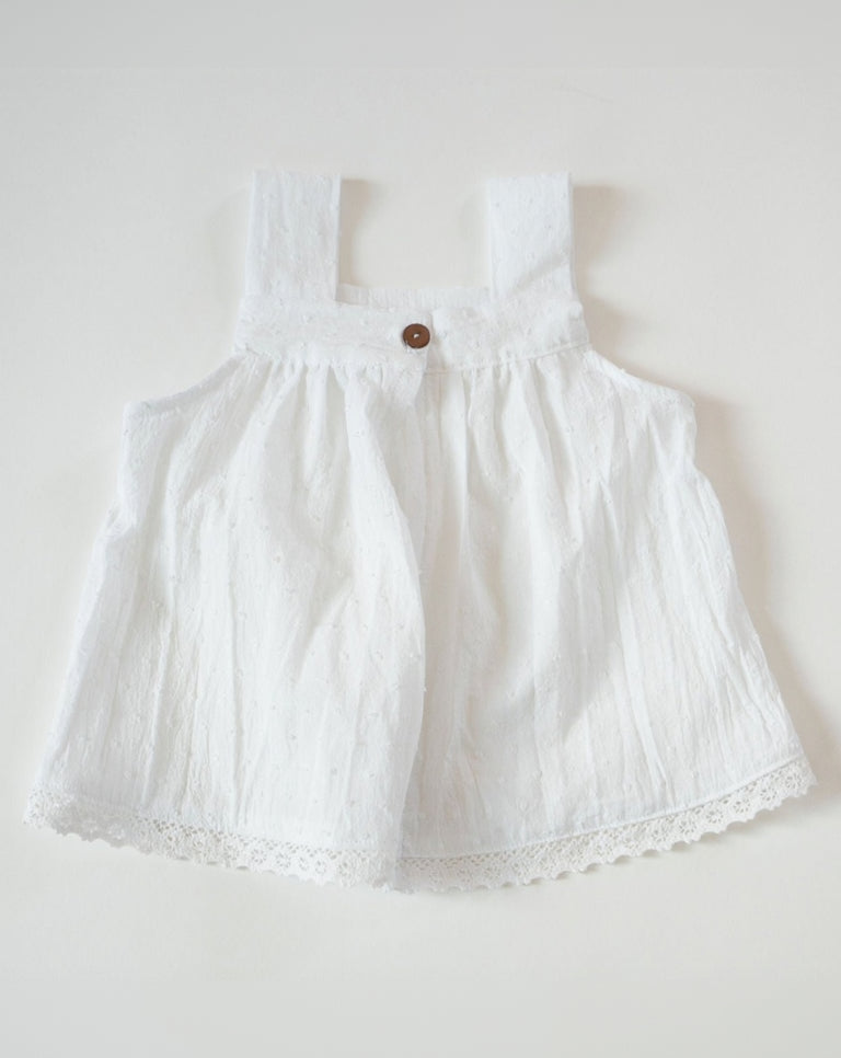 White baby dress with lace details on a light gray background