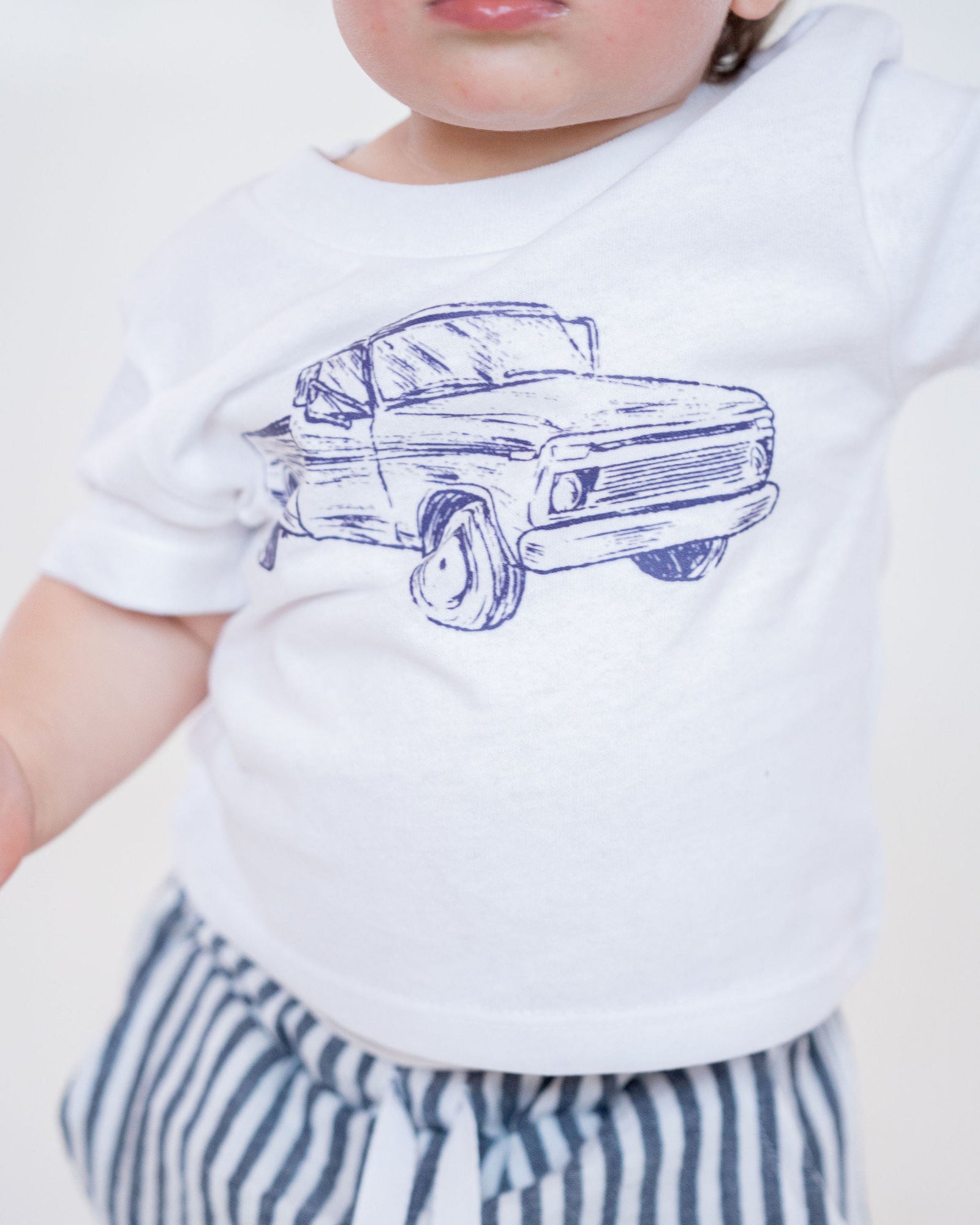 White t-shirt with a blue truck graphic on a white background