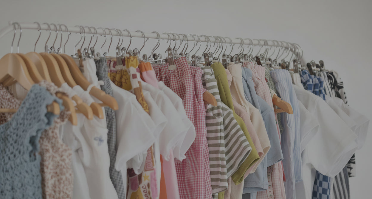 Display of colorful children's clothing on hangers against a white background