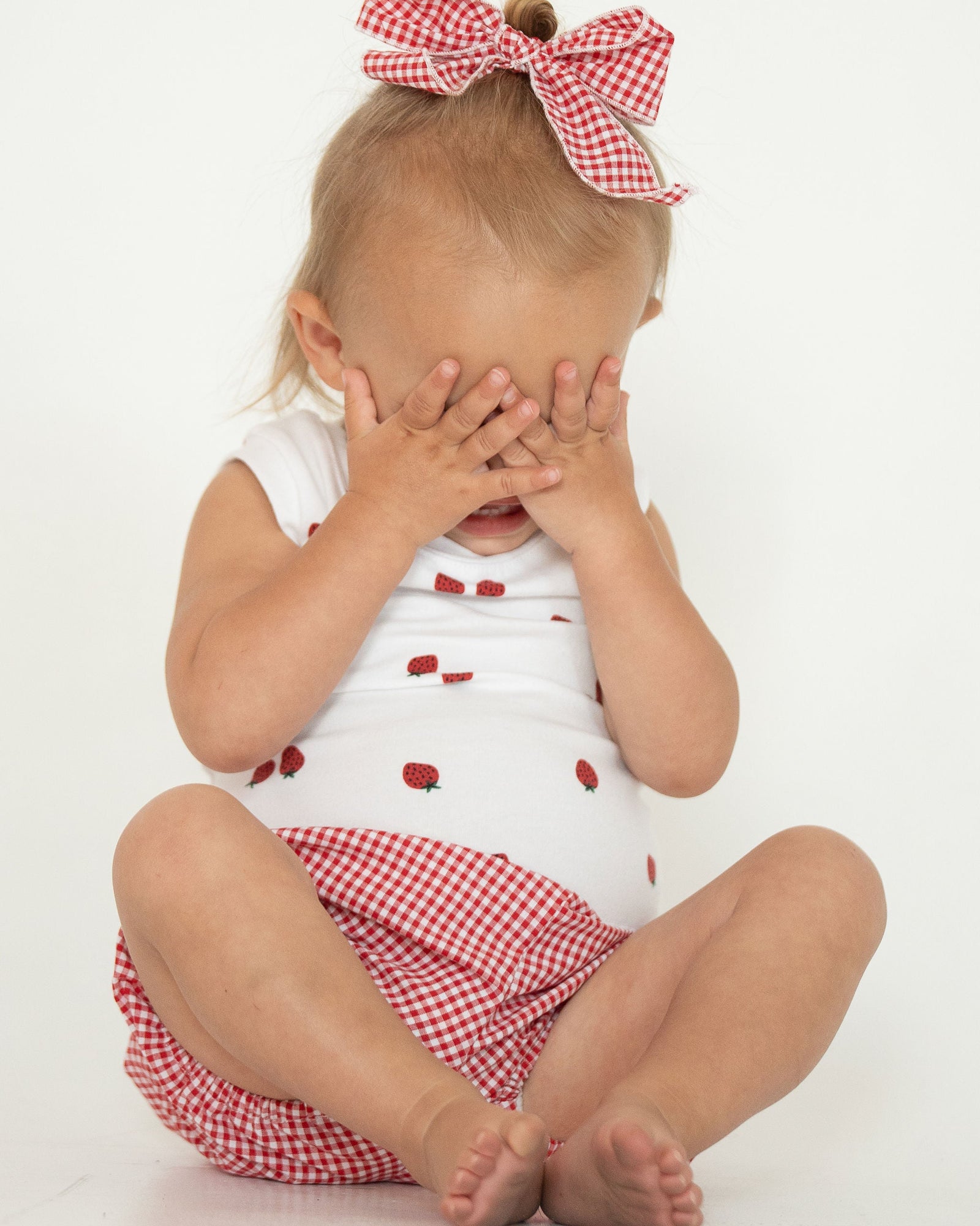 White sleeveless top with red strawberries on a white background
