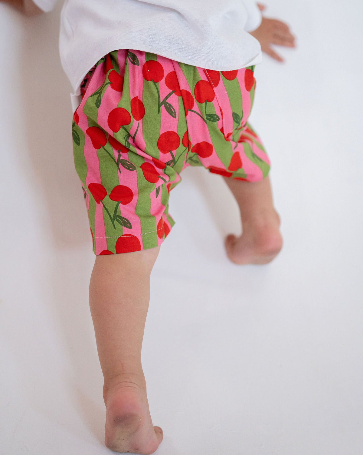 Child wearing cherry-patterned shorts on a white background